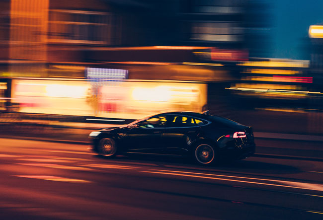 Voiture en mouvement avec un arrière-plan flou, indiquant un grand excès de vitesse.