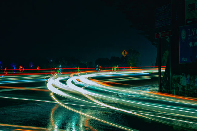 Lumières de voiture en mouvement sur la route avec flou, indiquant un grand excès de vitesse.
