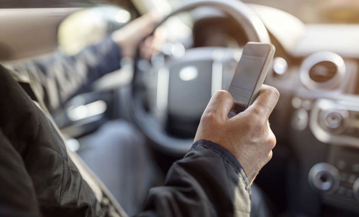 A man holding his cell phone while driving.