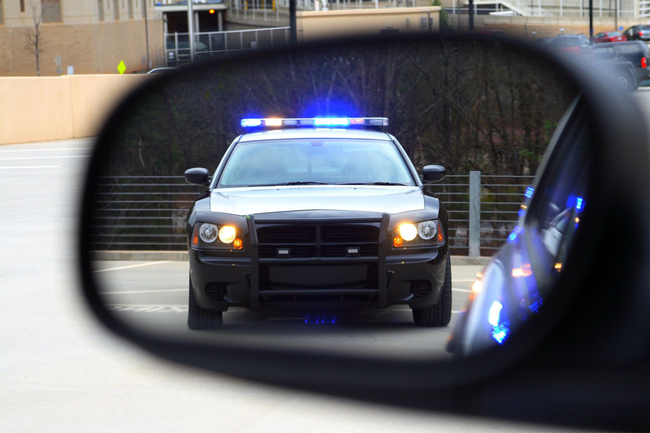 Voiture de police réfléchie dans le miroir latéral.